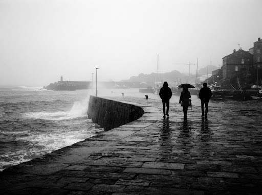 Niebla en el dique de poniente - Siluetas de caminantes en el espigón bajo la lluvia